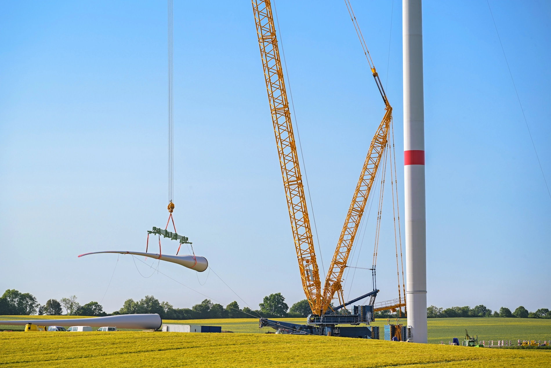 Raupenkran hebt ein Rotorblatt einer Windkraftanlage